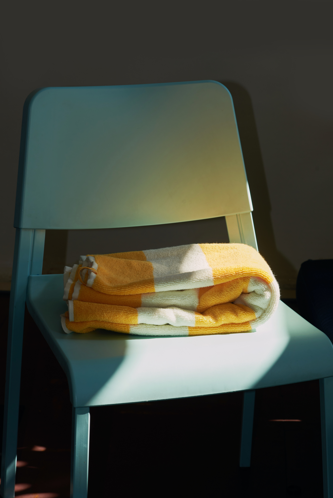 푸른 의자 위에 놓인 노랑 줄무늬 수건, 비스듬히 드는 햇빛